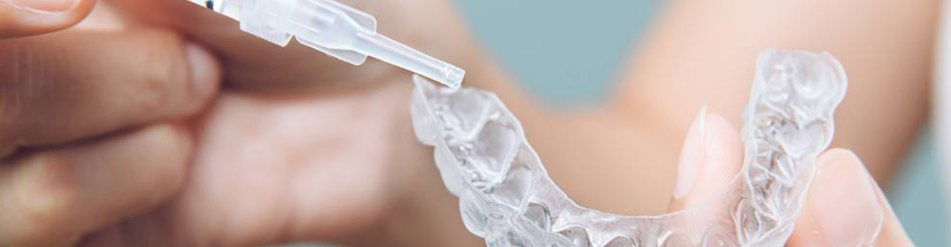 hands injecting whitening gel into clear tray.